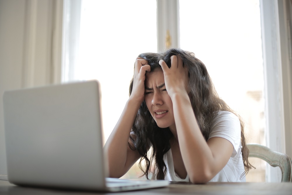 femme devant son ordinateur en plein stress mains sur la tête