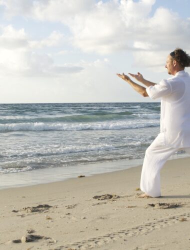 Homme pratiquant le tai chi sur la plage