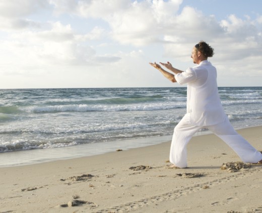 Homme pratiquant le tai chi sur la plage