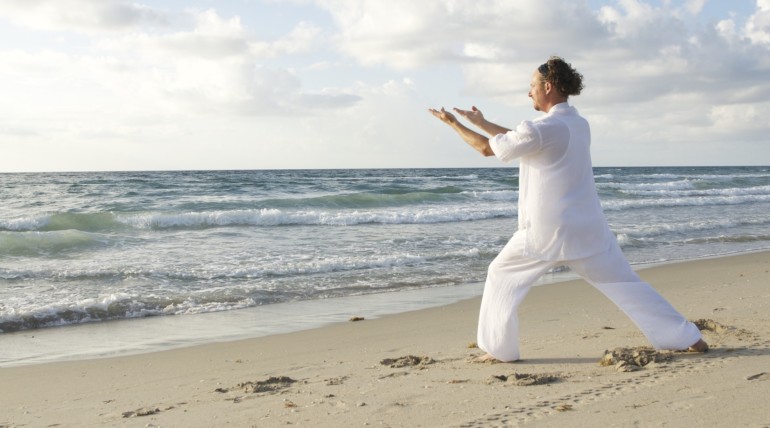 Homme pratiquant le tai chi sur la plage