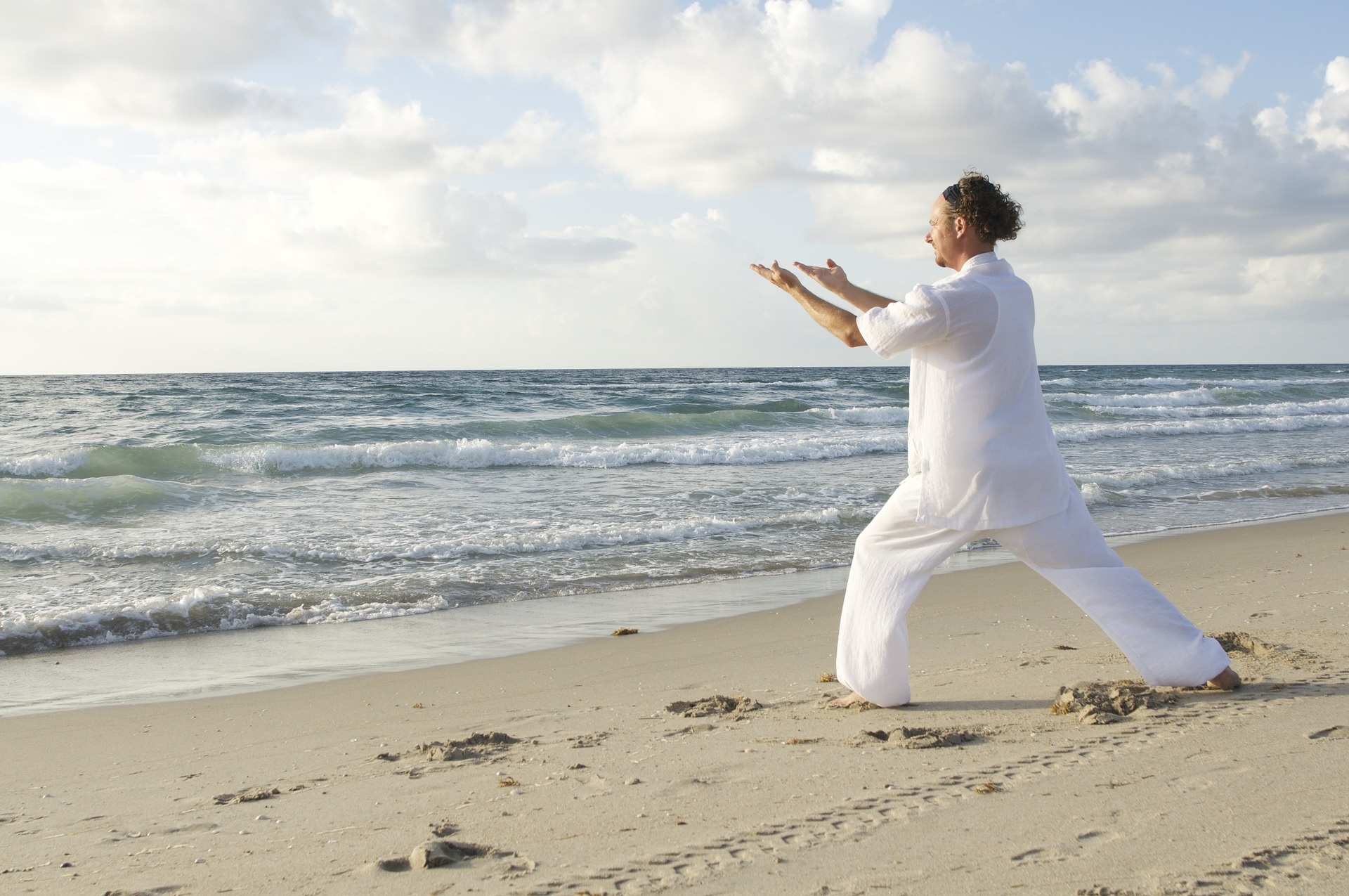 Homme pratiquant le tai chi sur la plage