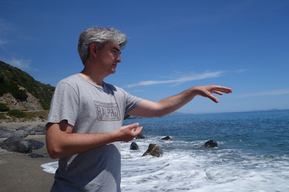 Xavier Bénard réalisant un geste de qi gong sur une plage en Crête